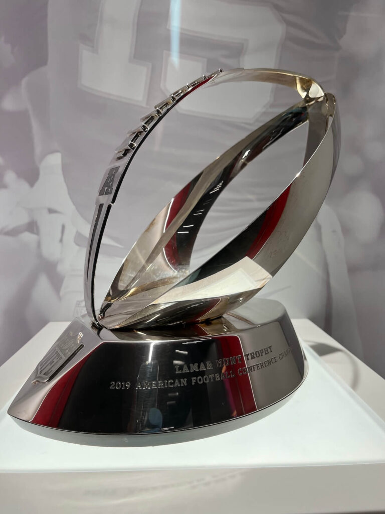 Shiny silver Lamar Hunt Trophy with a football-shaped design on a base engraved with '2019 American Football Conference Champion.'