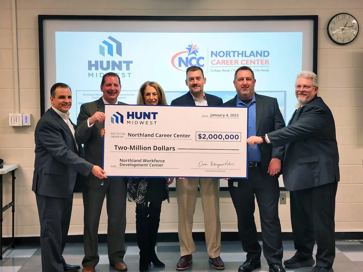 Six people in business attire hold a large ceremonial check for $2,000,000 made out to Northland Career Center from Hunt Midwest.