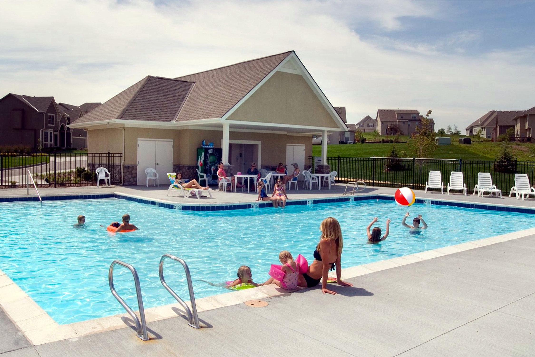 Children and families enjoy a summer day in the neighborhood pool at their Hunt Midwest master planned new home community.